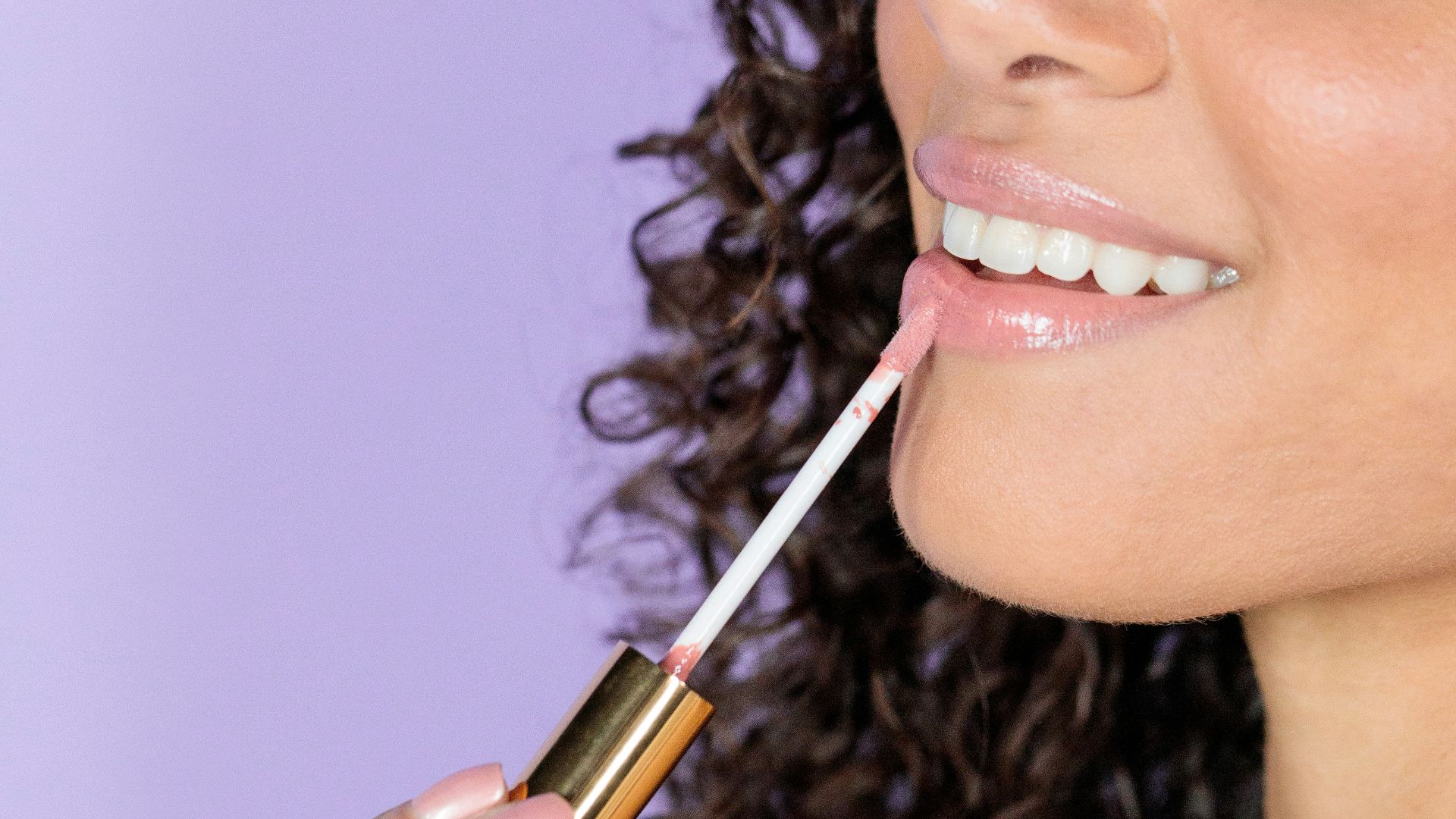 woman holding black and gold lipstick