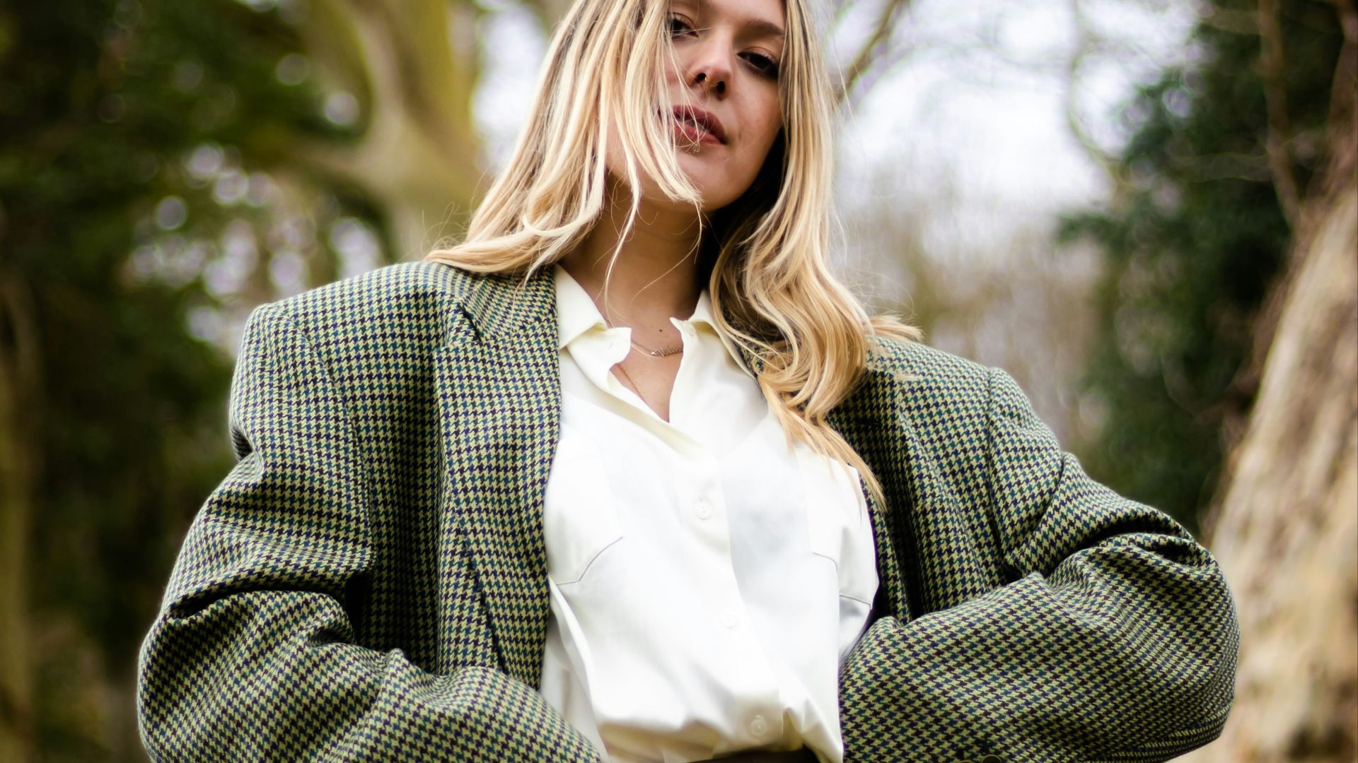 woman in gray and white polka dot blazer standing and smiling
