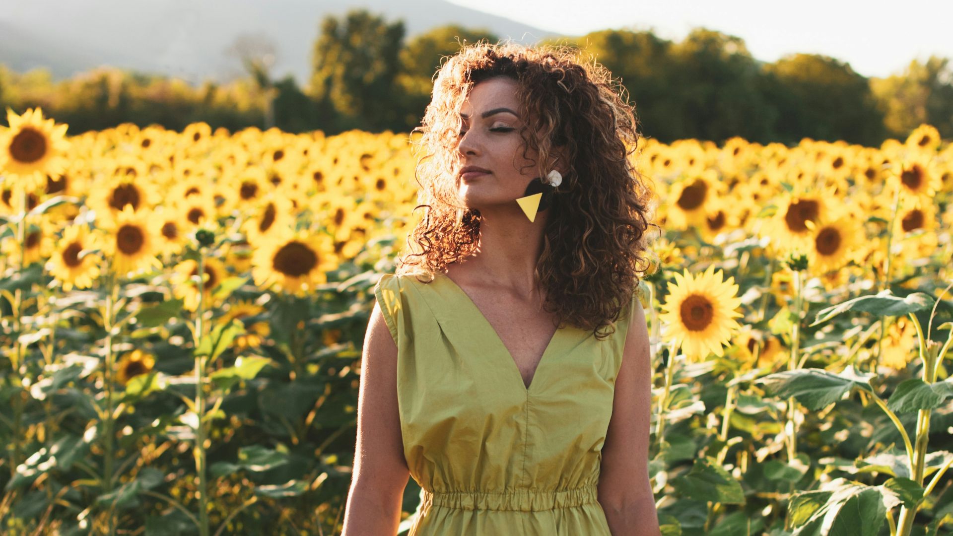 woman in yellow sleeveless dress holding white and black hair brush standing on yellow flower field