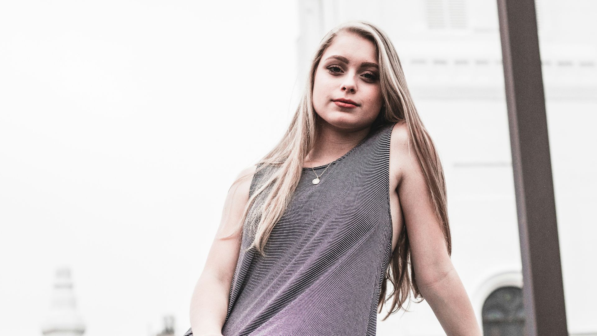 woman sitting near brown wooden pillar outdoor during daytime