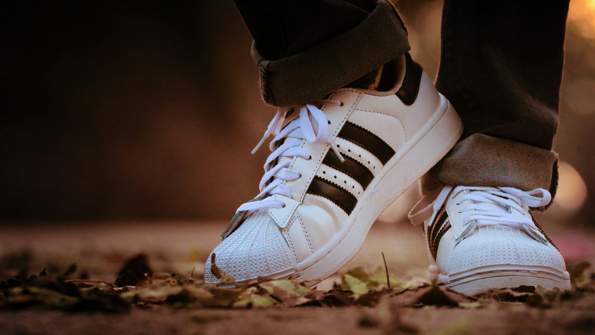person wearing pair of white adidas Superstar sneakers during daytime