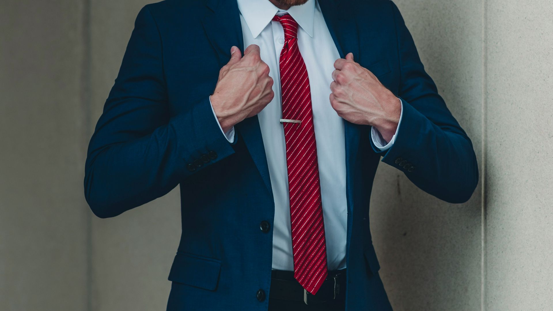 a man in a suit and red tie tying his tie