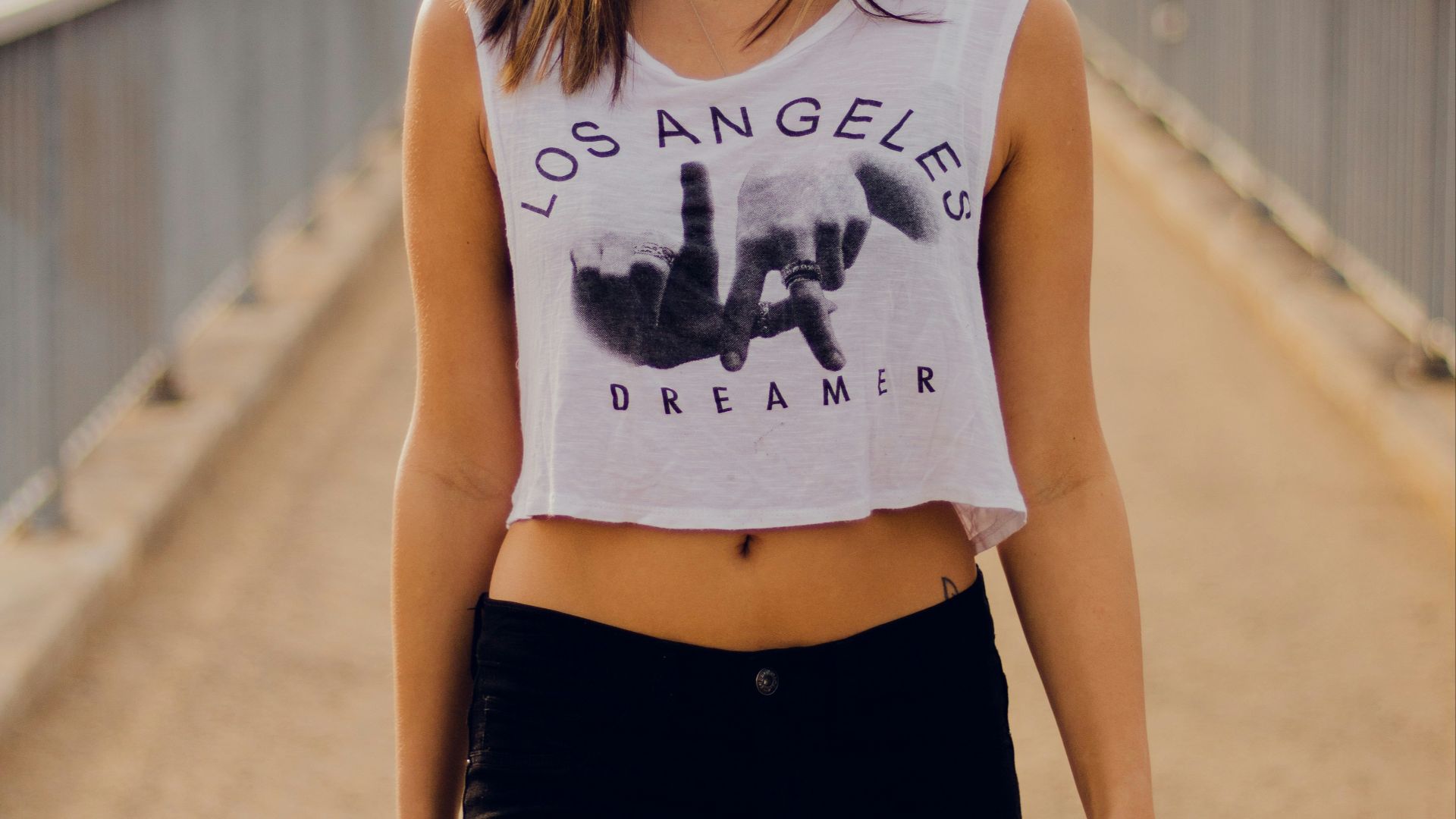 woman in white crop top standing on bridge