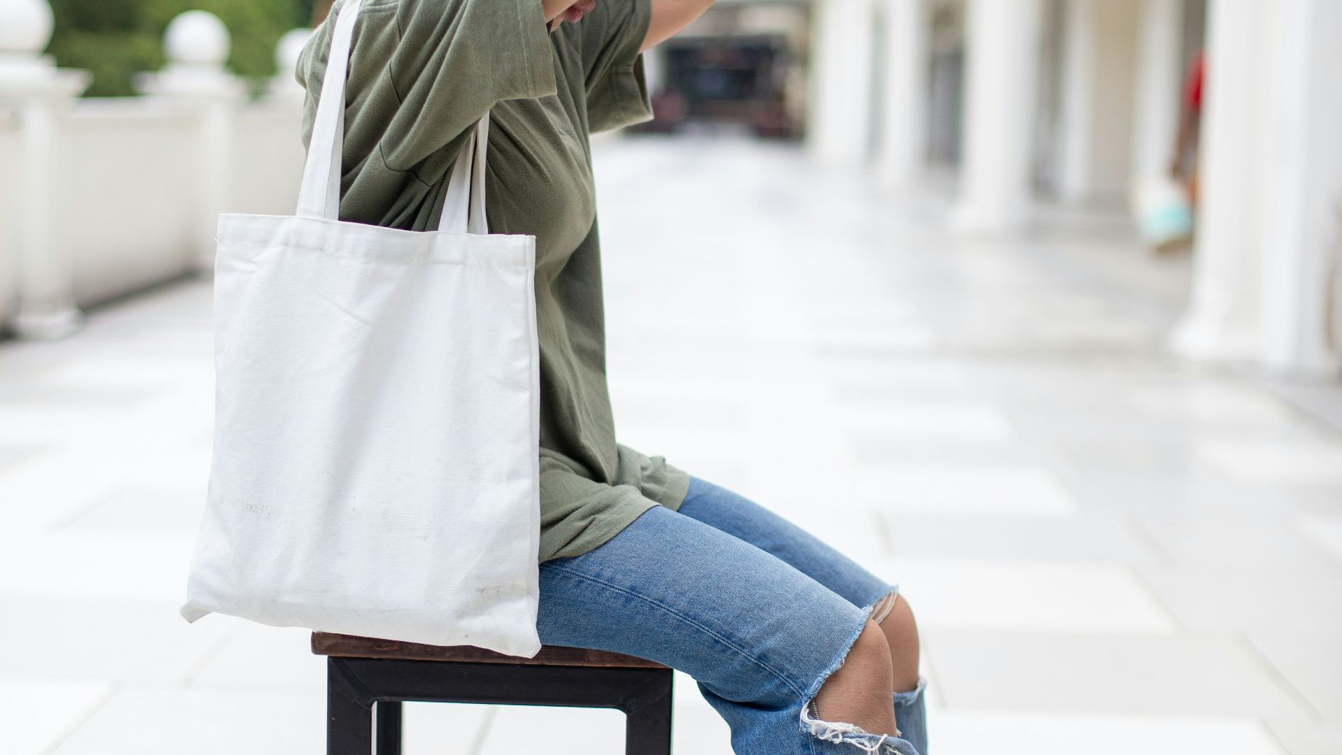 woman in gray jacket and blue denim jeans sitting on brown wooden chair