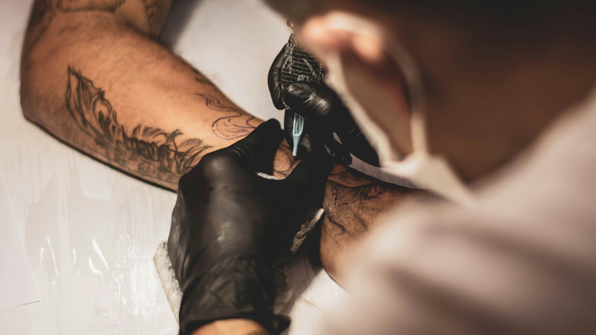 shallow focus photo of person tattooing person's right arm