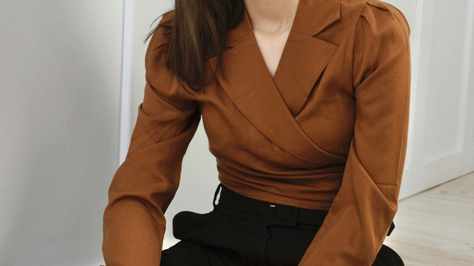 woman in brown blazer and black skirt sitting on white floor