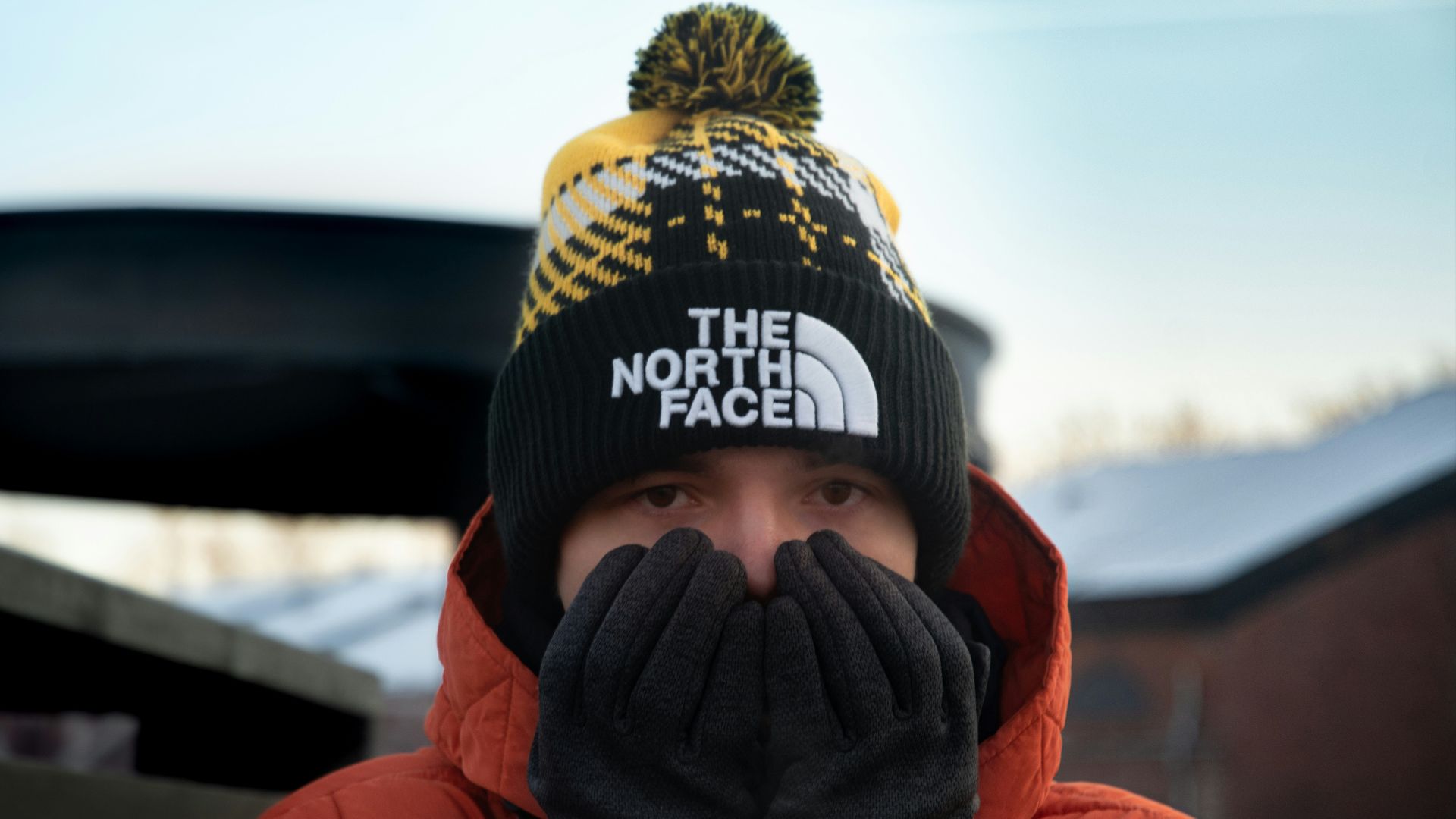 person in red hoodie wearing black and yellow knit cap