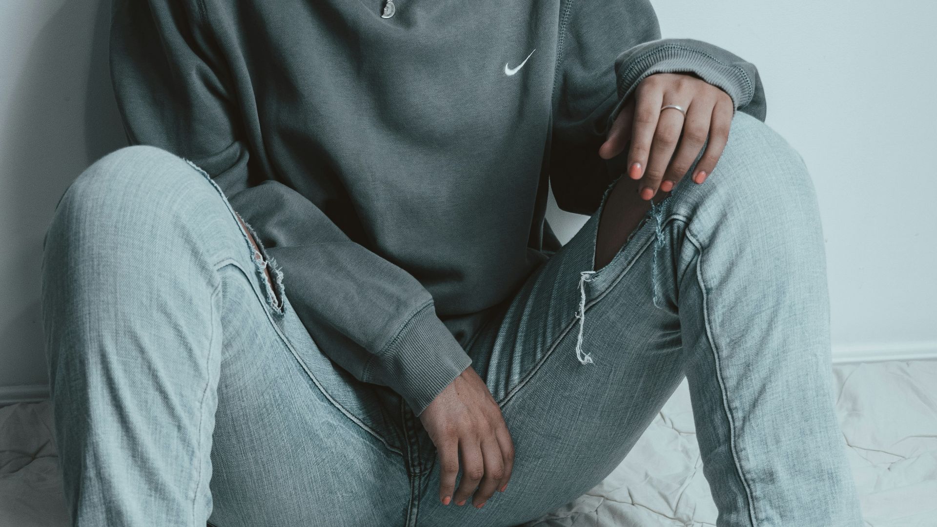 man in gray sweater and gray denim jeans sitting on bed