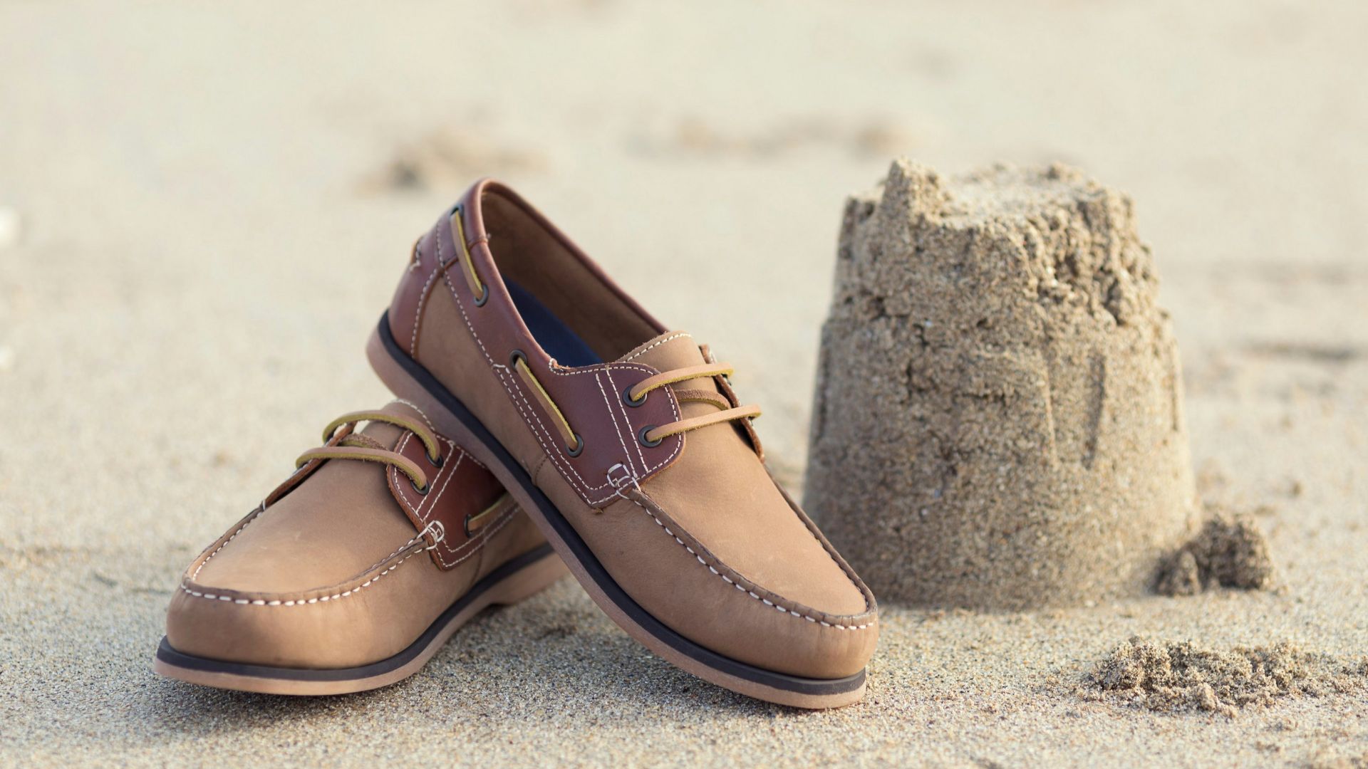 a pair of brown shoes sitting on top of a sandy beach