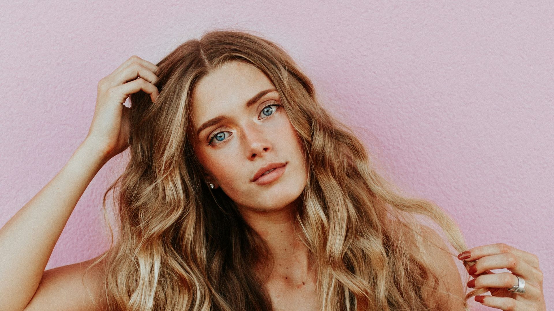 woman standing next to pink wall while scratching her head
