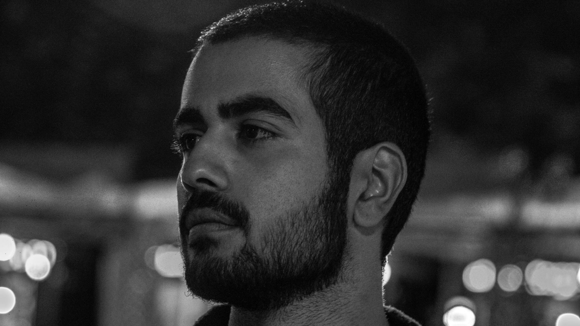 a man with a beard standing in a dark room