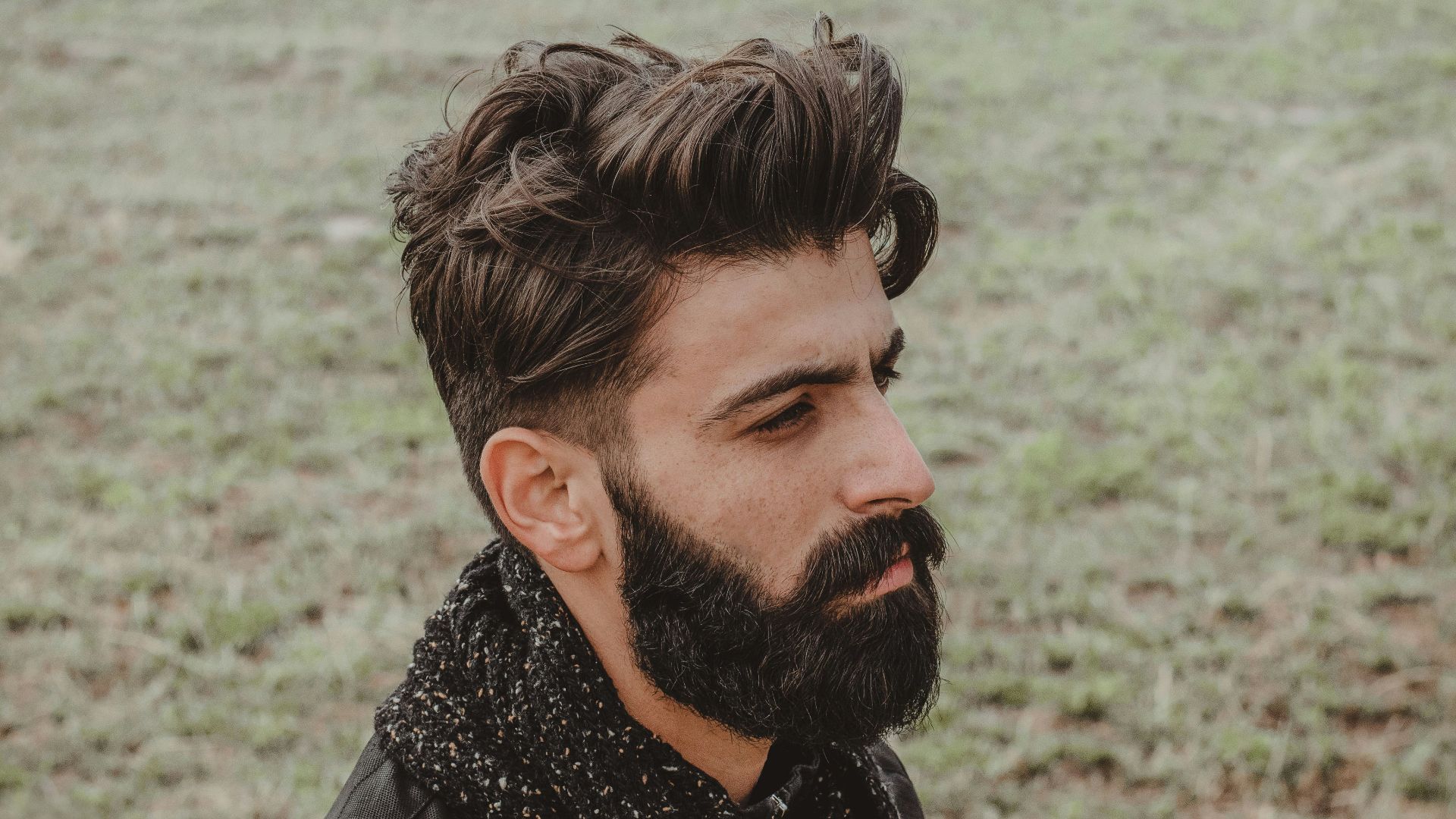man in black leather jacket standing near body of water during daytime