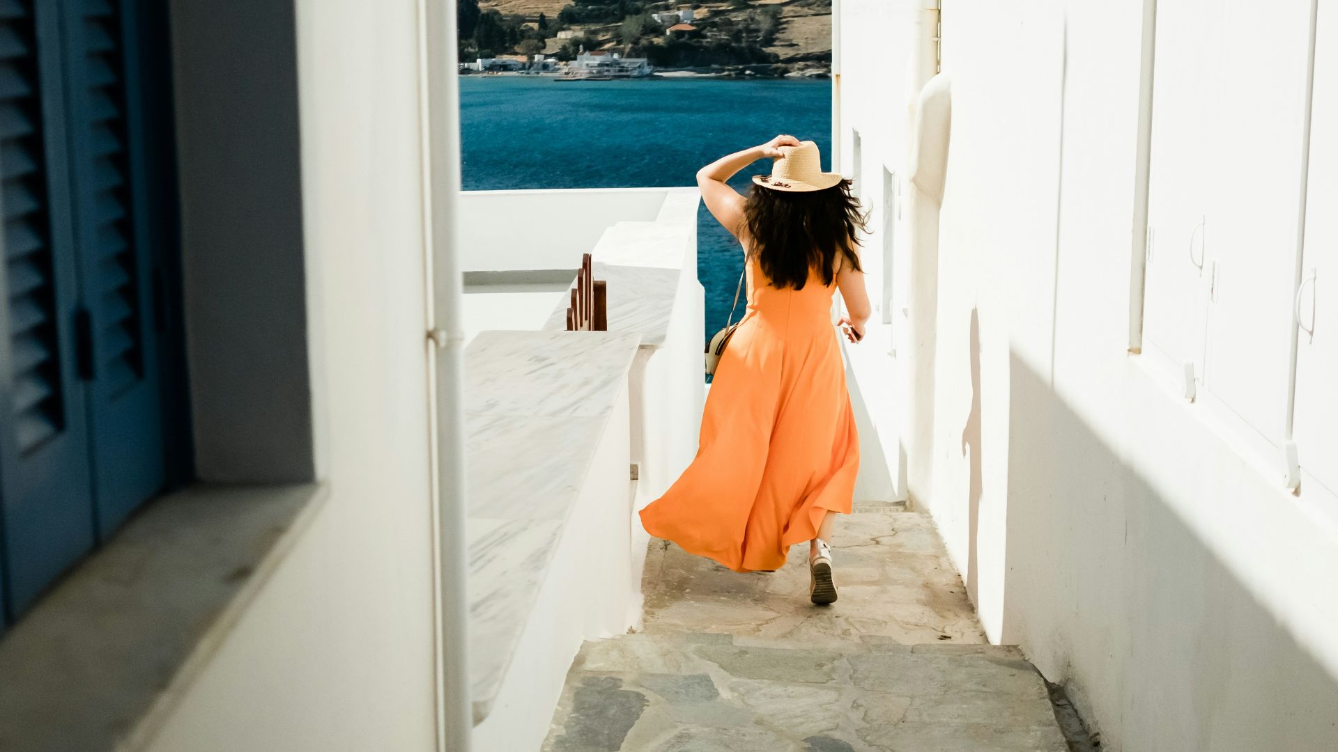 woman in orange sleeveless dress running through srairs