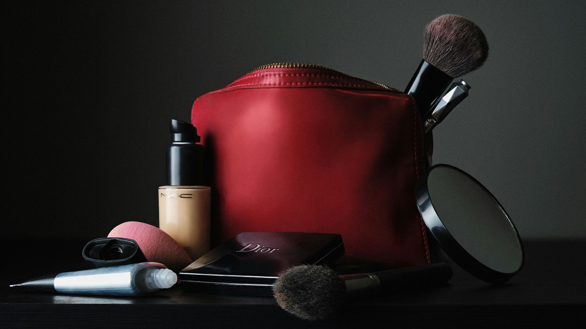red leather bag beside black makeup brush