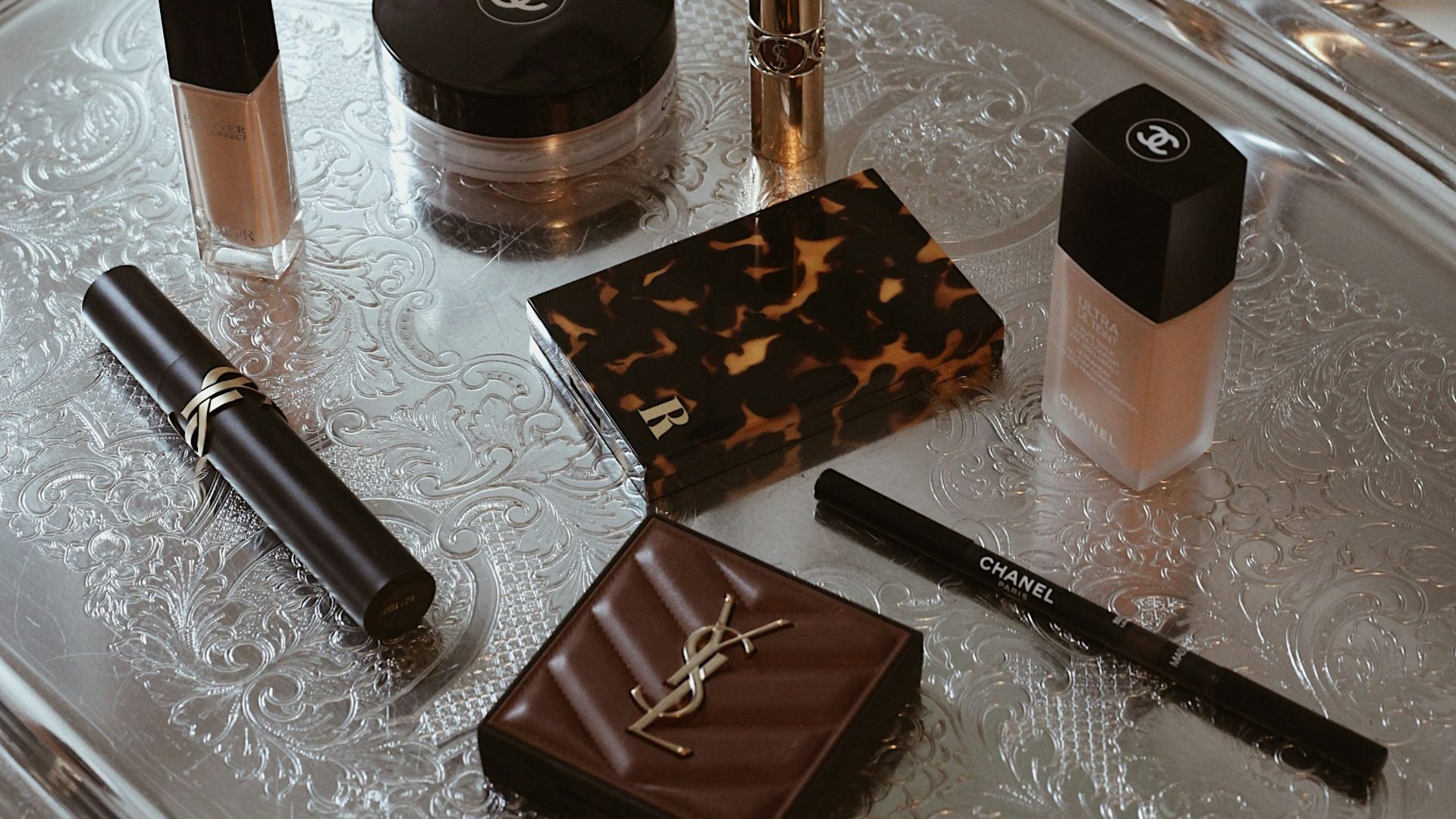 Makeup products are displayed on a decorative silver tray.