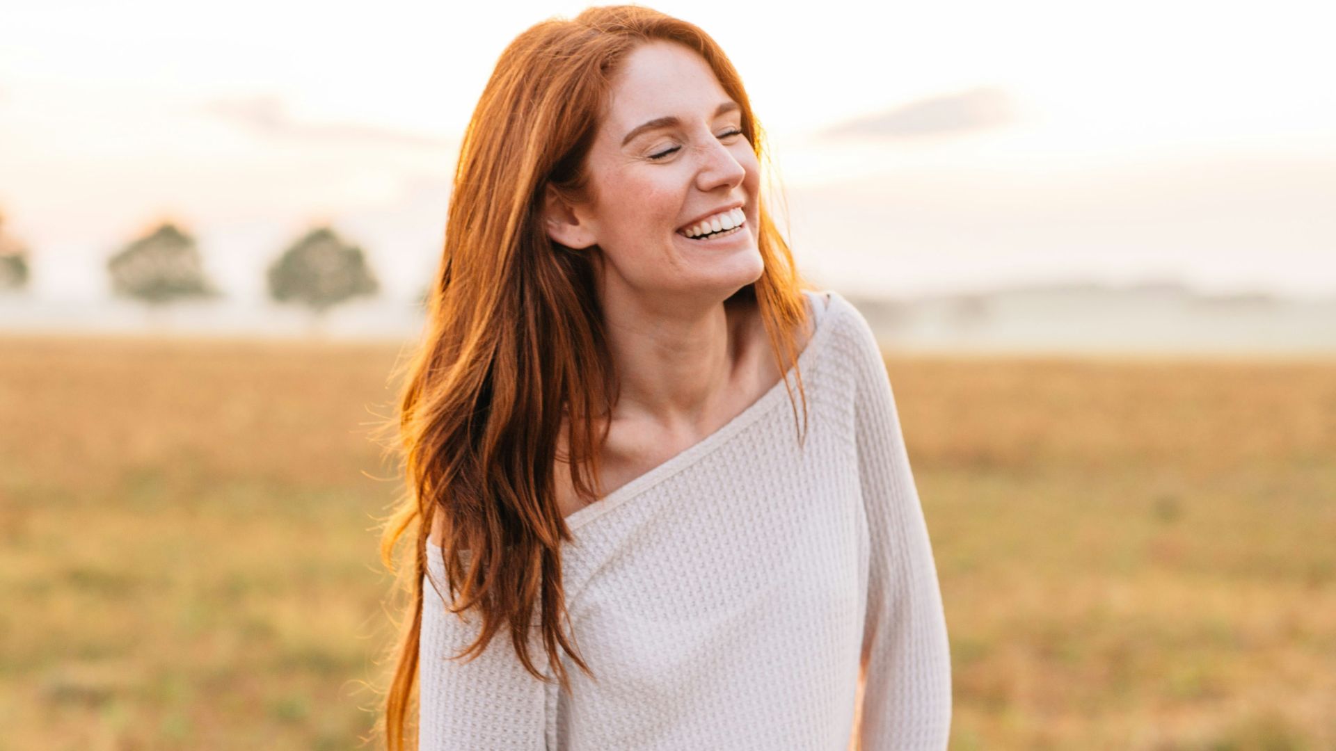 woman in white long sleeve shirt and blue denim jeans standing on green grass field during