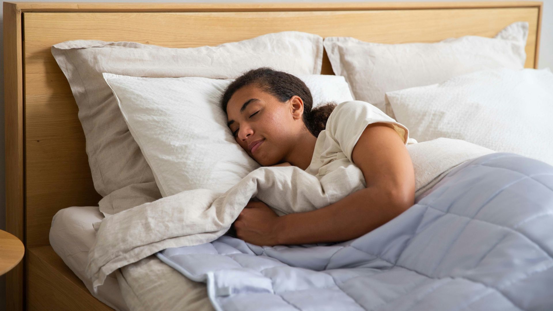 a young girl sleeping in a bed with white sheets