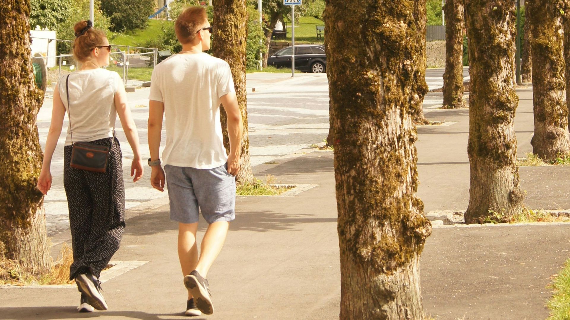man in white t-shirt walking on sidewalk during daytime