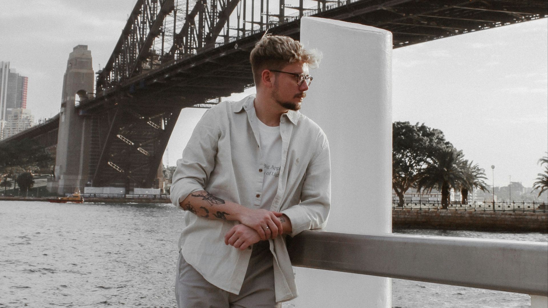 man in white dress shirt and white pants sitting on white wooden fence during daytime