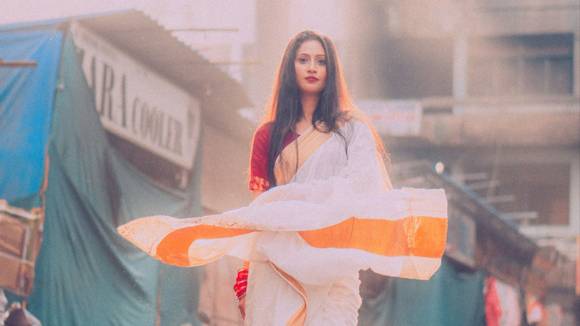 A woman in a white dress holding an orange and white umbrella
