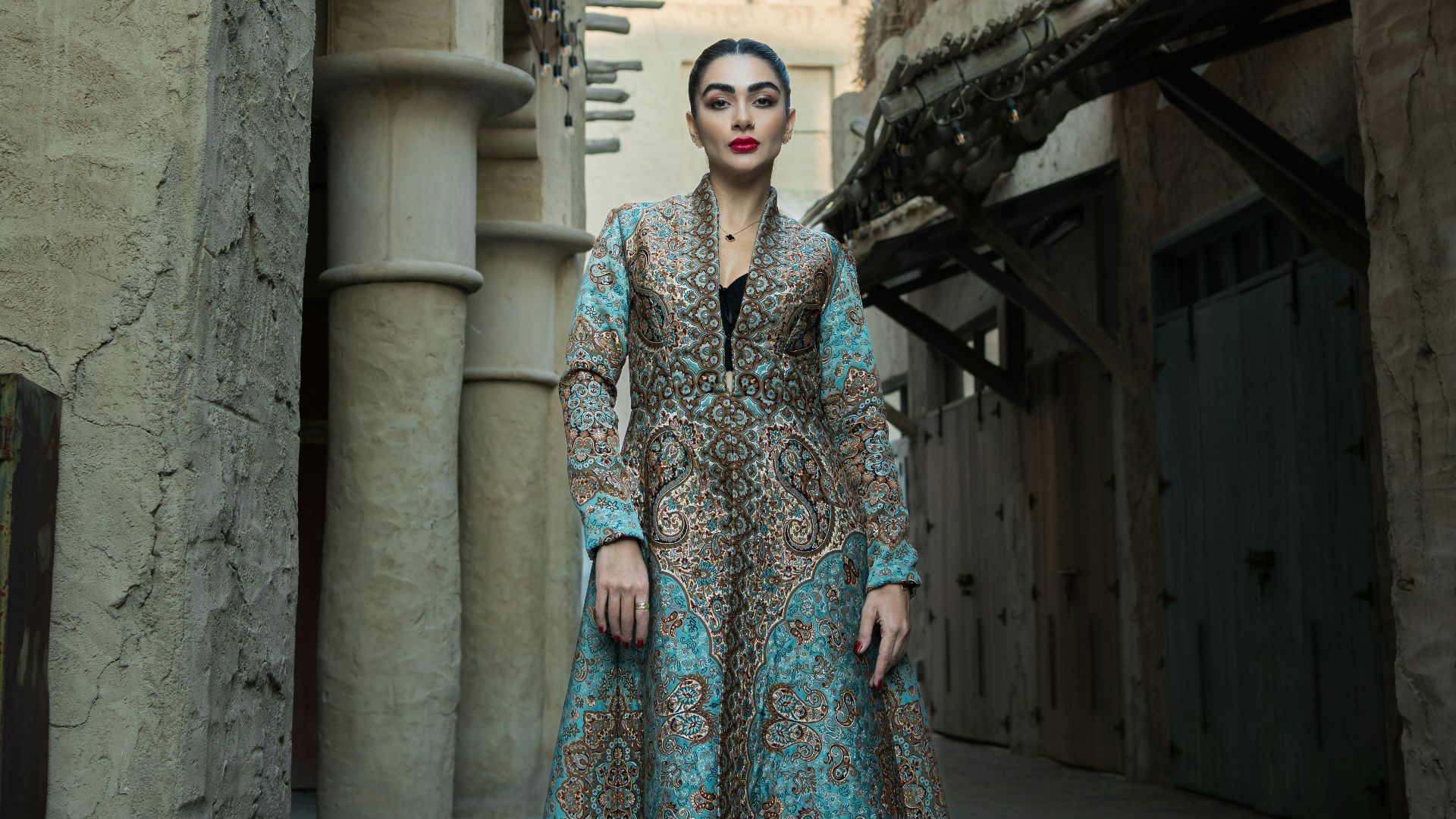 Woman in a dress stands in a narrow alleyway.