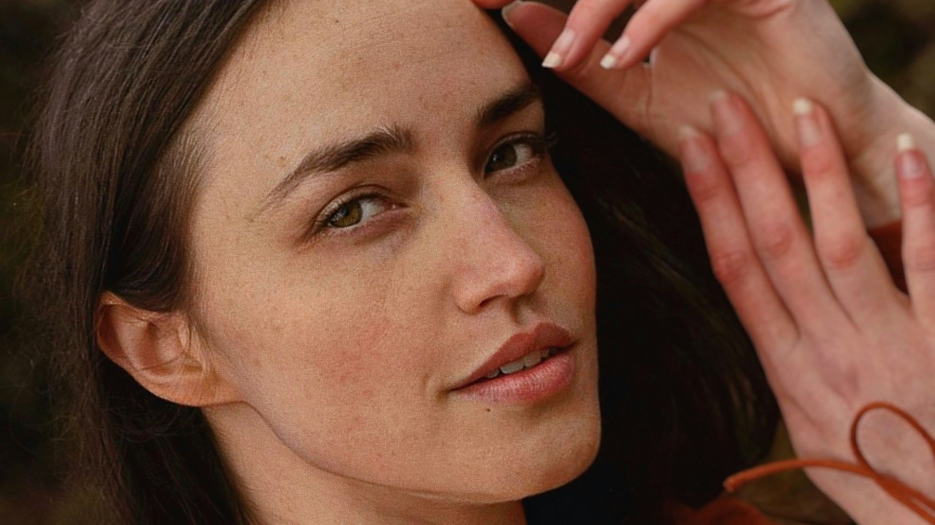 a close up of a person wearing a brown shirt