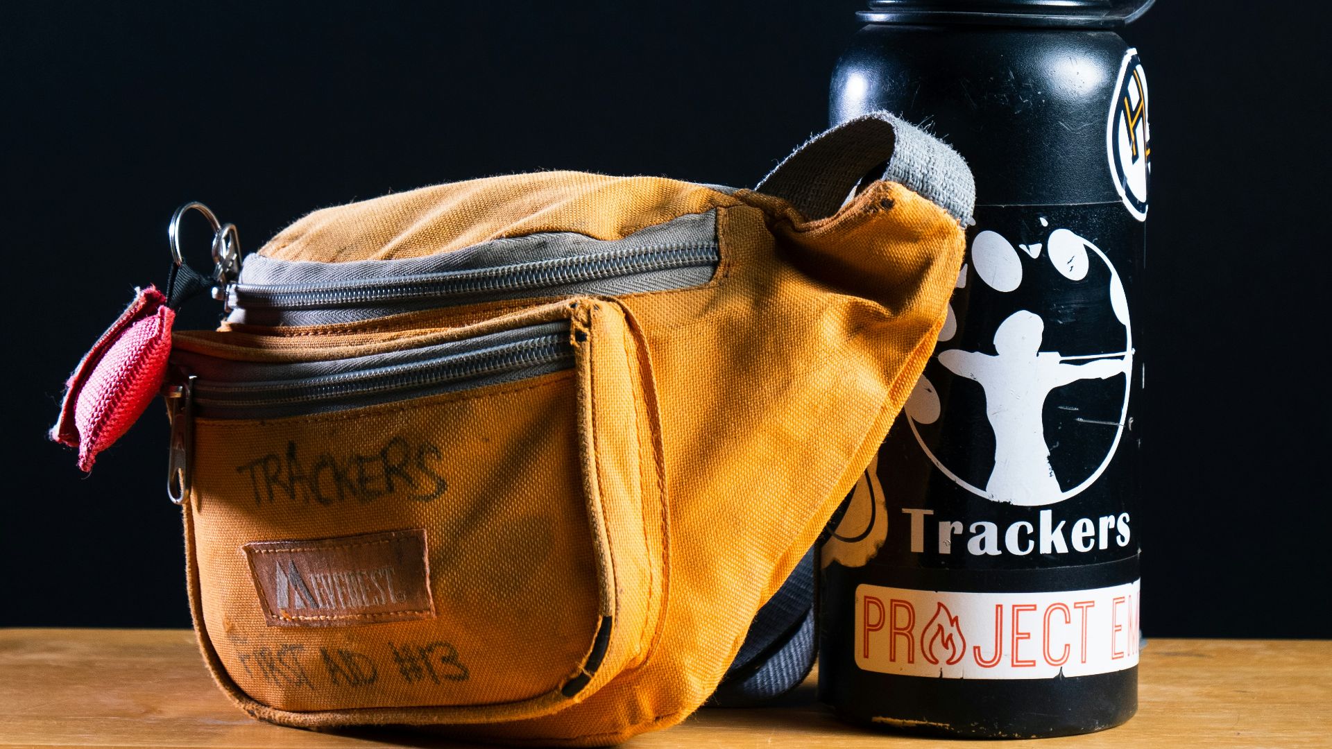 yellow Trackers fanny pack besides black water bottle