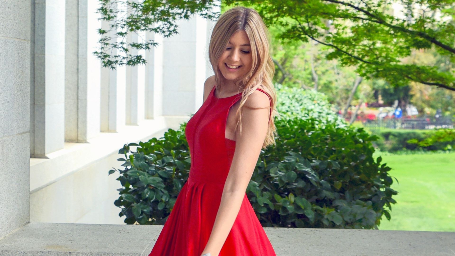 woman in red sleeveless dress standing on gray concrete floor during daytime