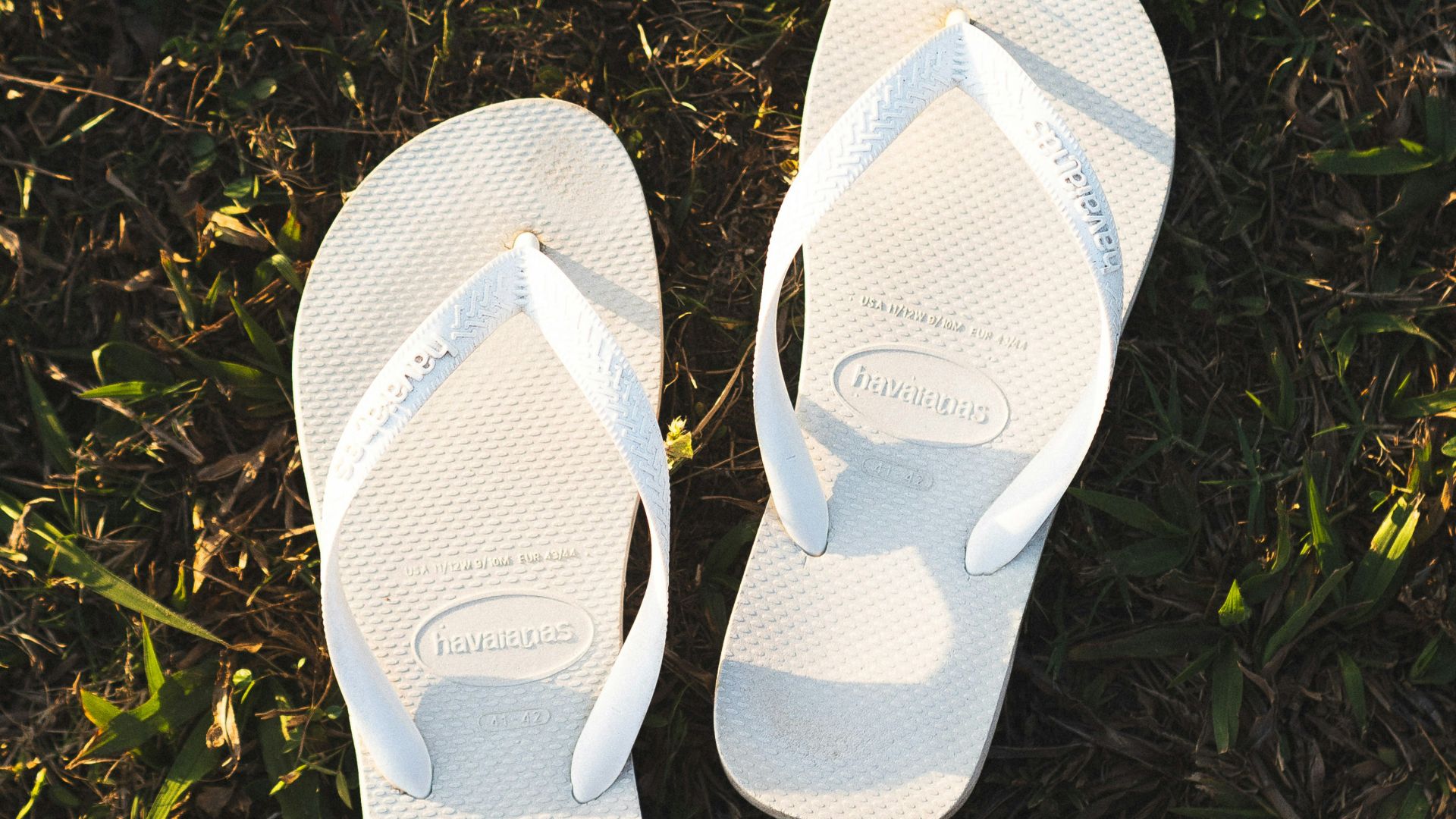 a pair of white slippers sitting on top of a lush green field