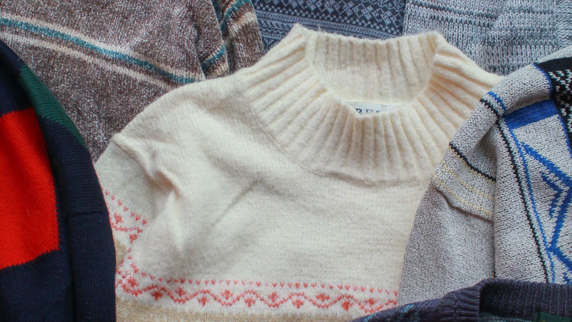 a pile of sweaters sitting on top of a bed