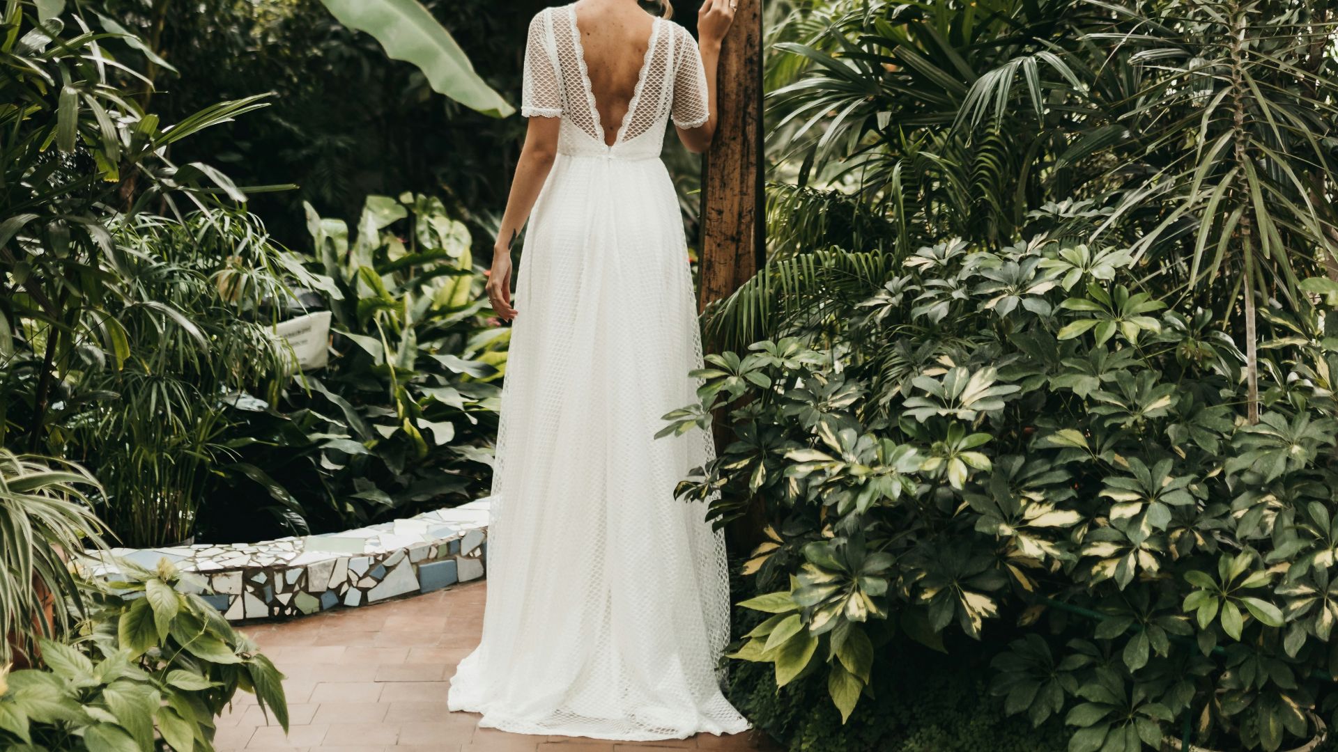 a woman in a white dress standing in a greenhouse