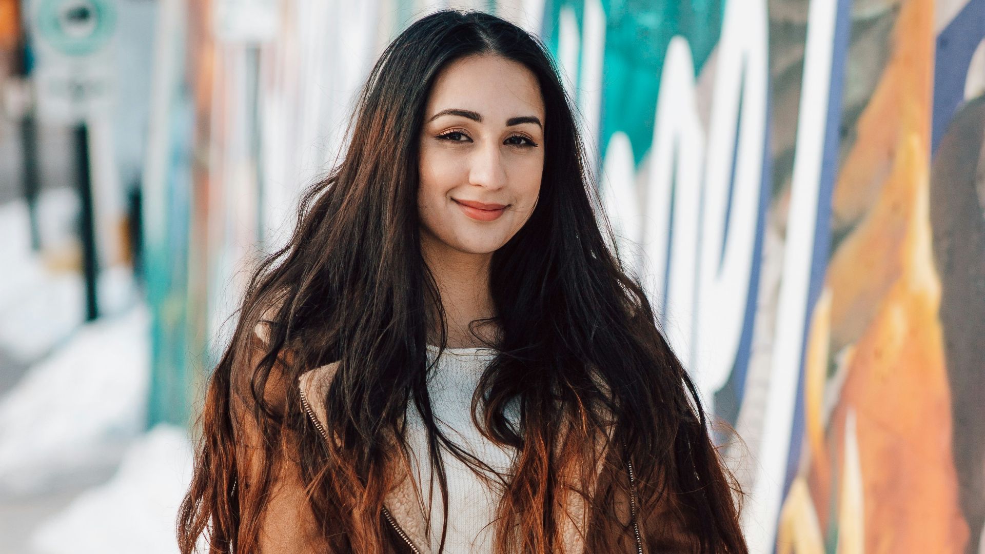 woman in brown coat standing on snow covered ground during daytime