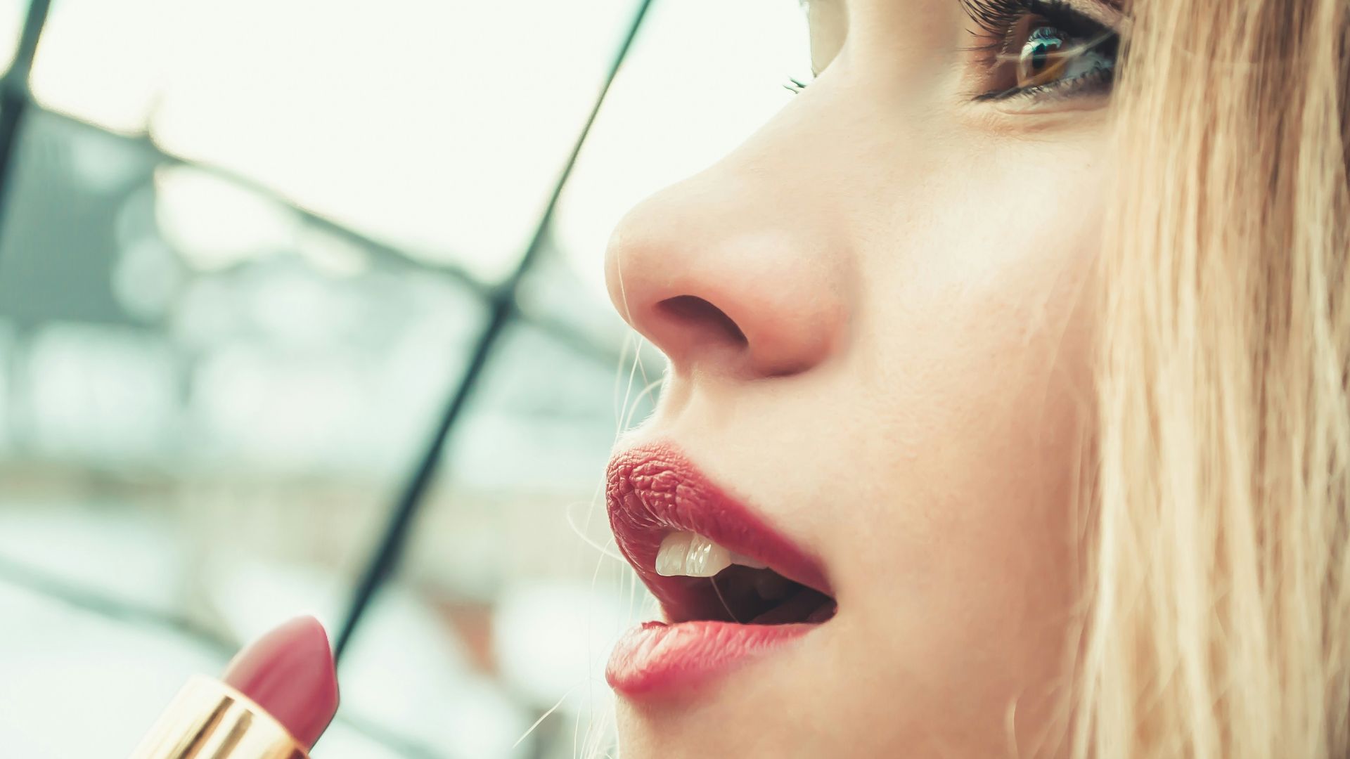selective focus photography of woman holding lipstick