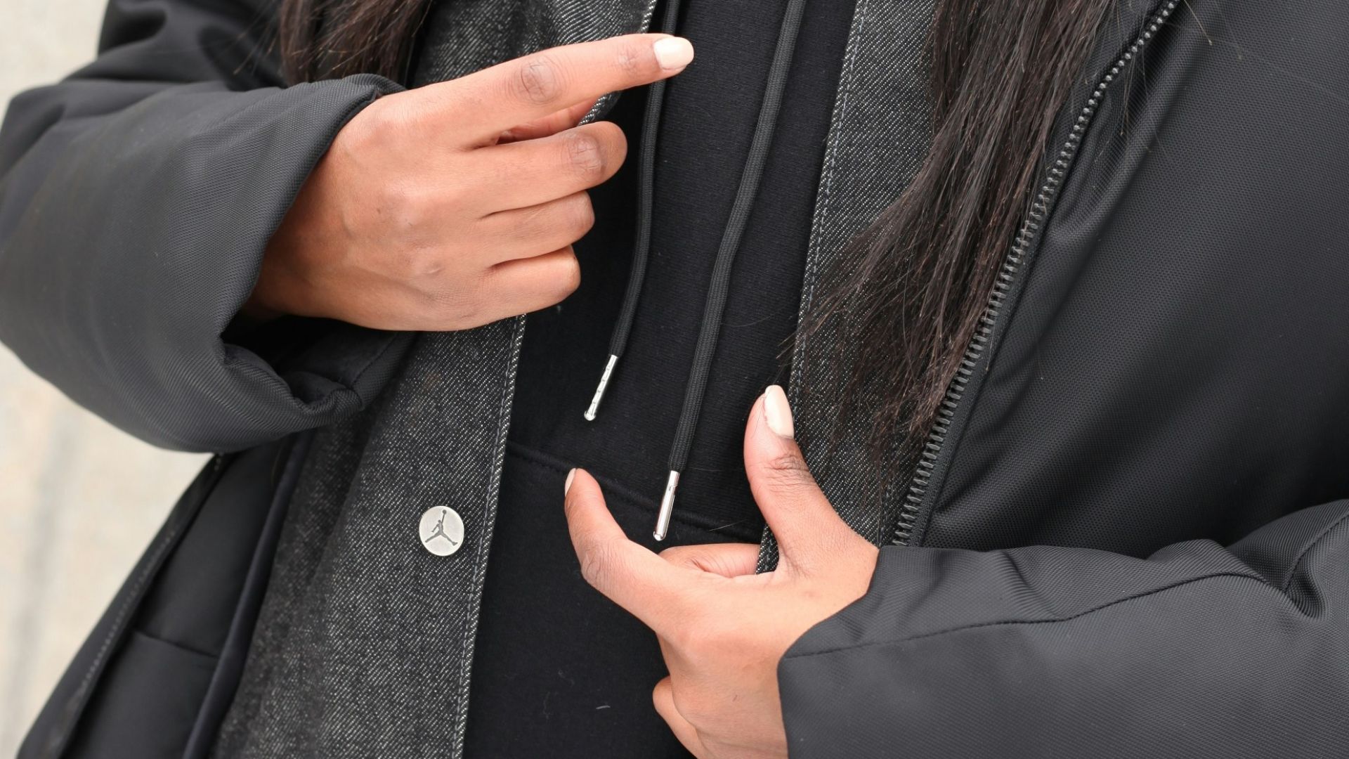 woman in black coat holding her chin