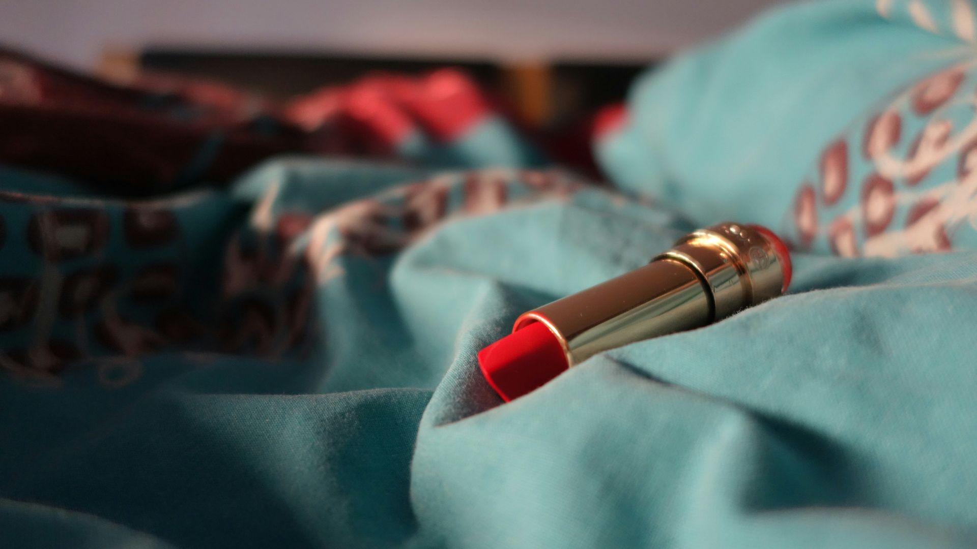 a red lipstick resting on a blue blanket