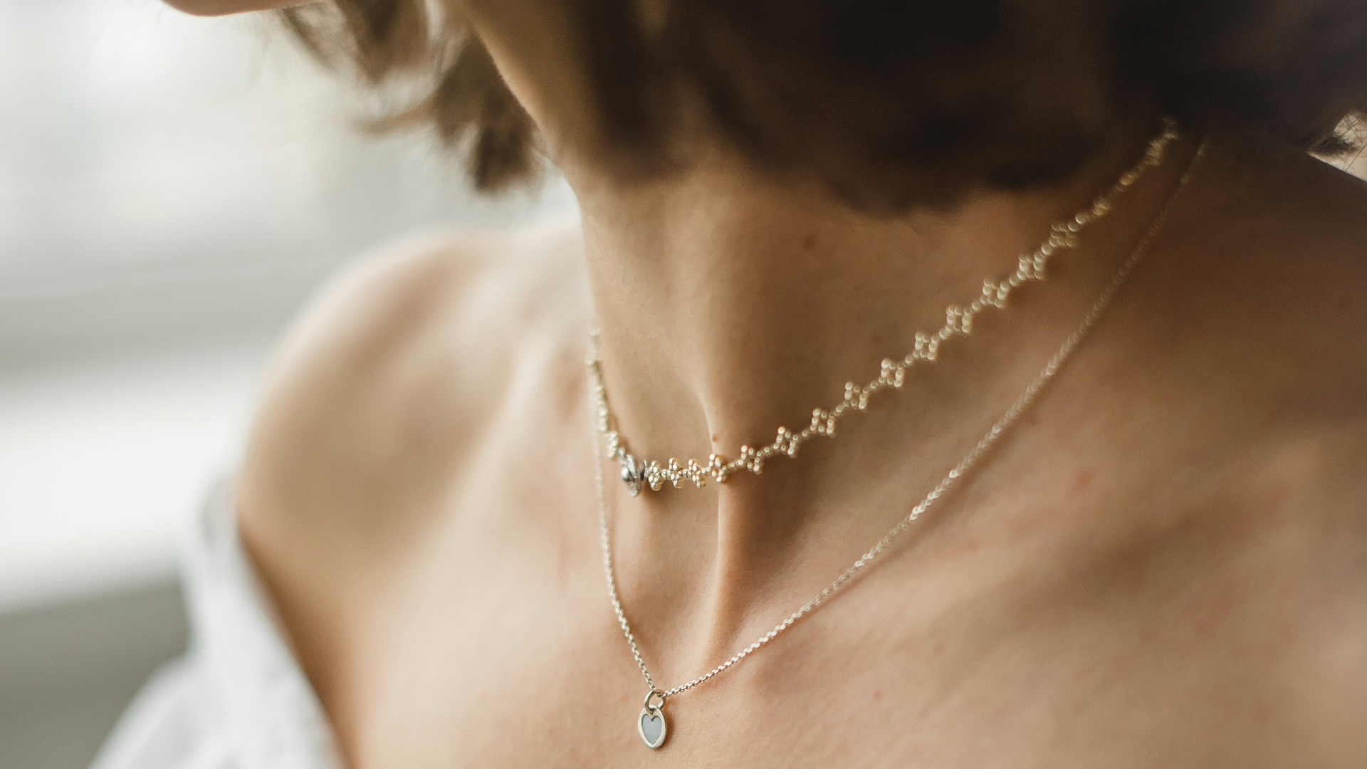 woman in white off shoulder shirt wearing silver necklace