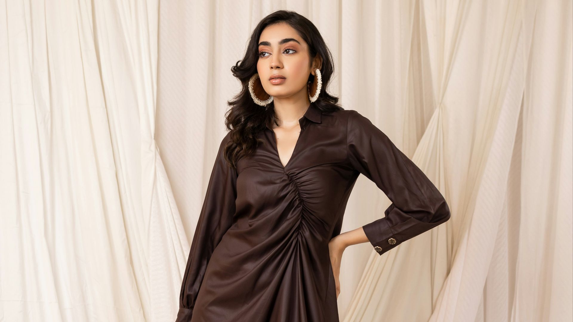 Woman in a stylish brown ruched dress with accessories.