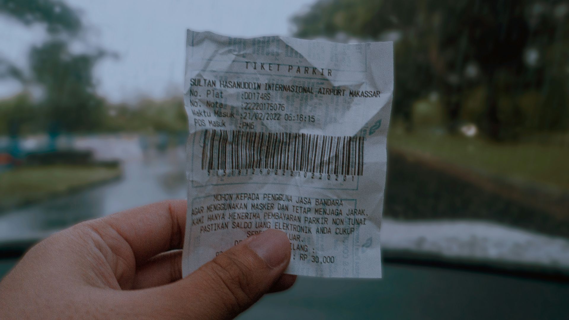 a hand holding a piece of paper with a bar code on it