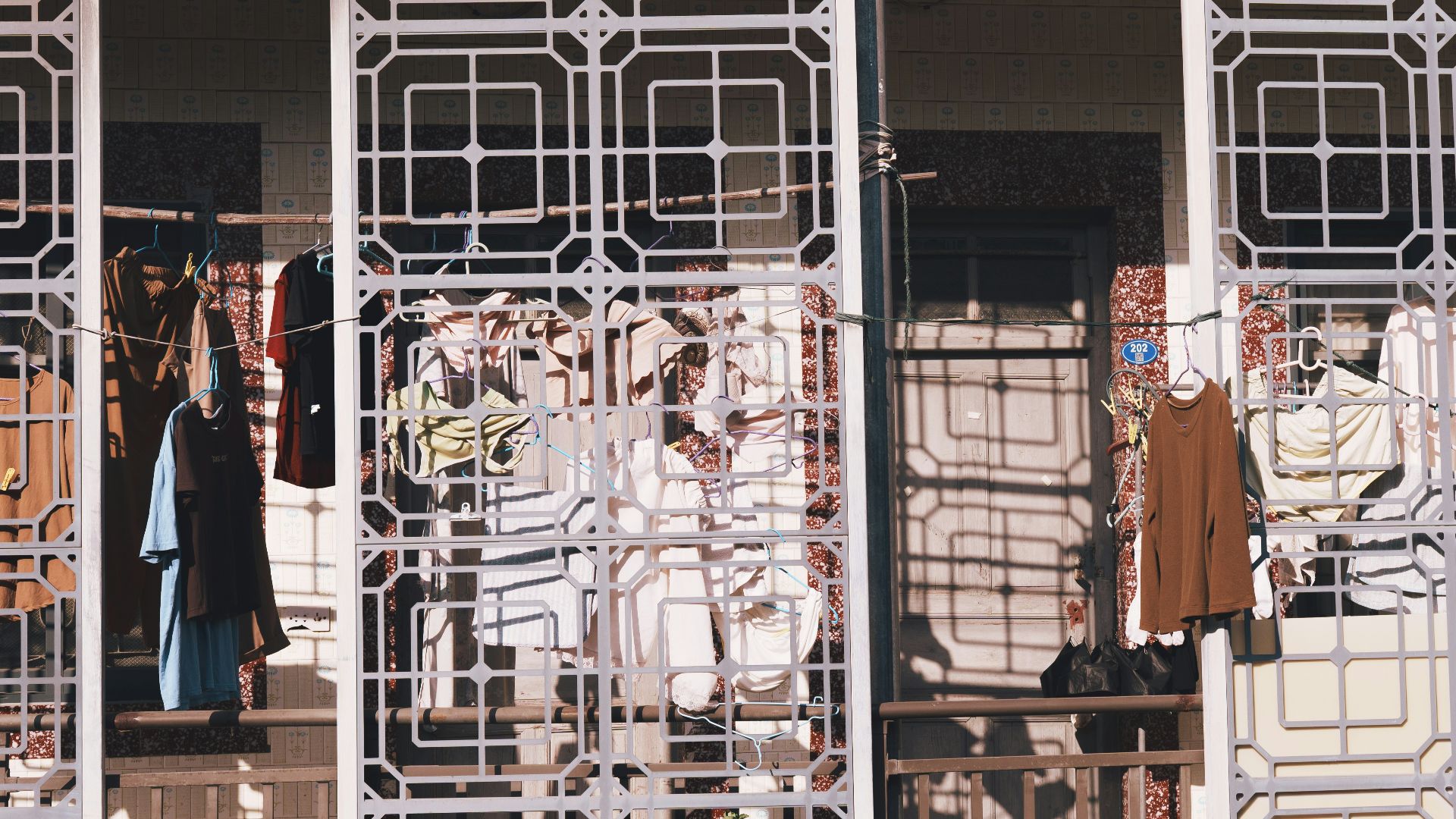 Clothes drying on a balcony behind decorative screens.