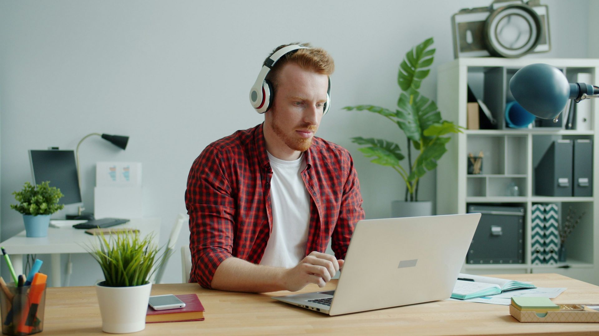 Man with headphones working on laptop at desk.