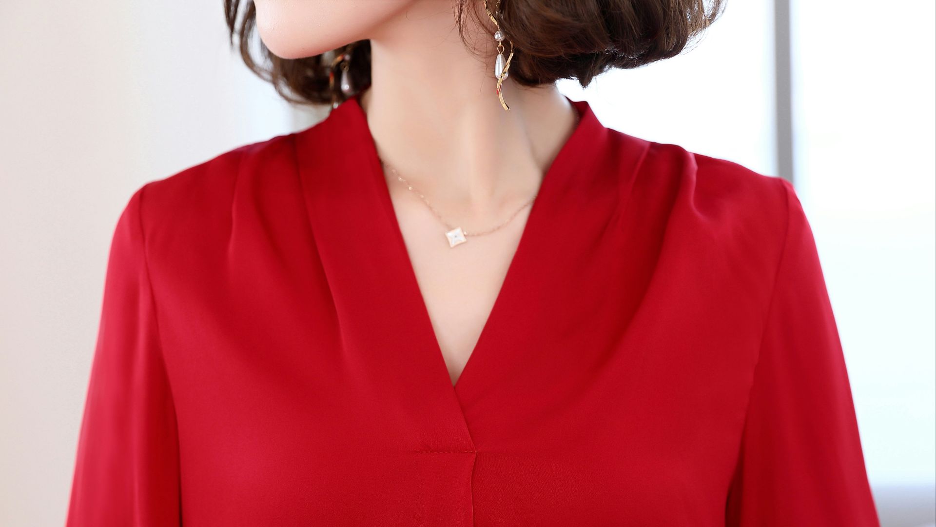 A woman in a red blouse with a necklace.