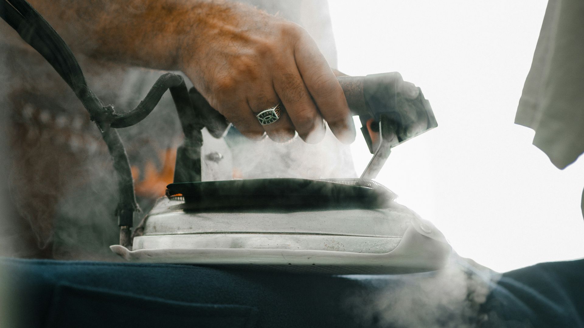 Man irons clothes with a vintage iron.