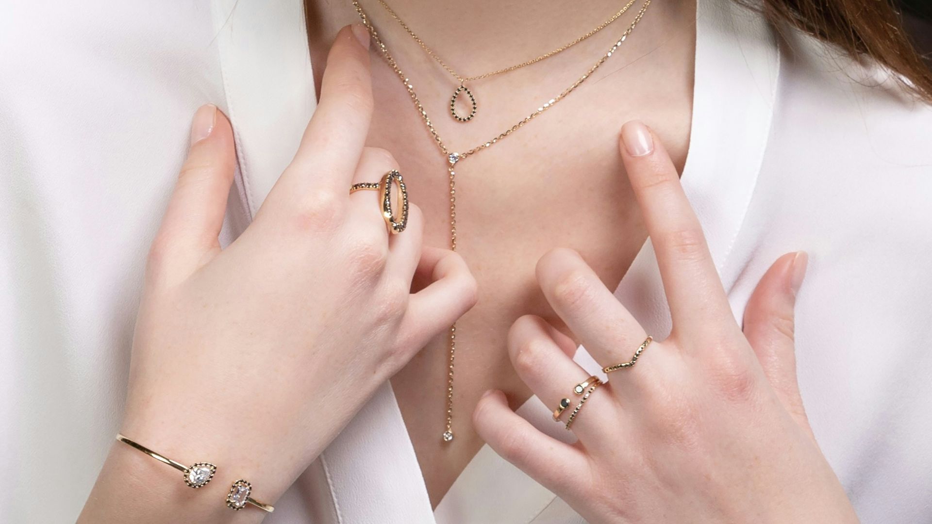 a close up of a person wearing rings and a necklace