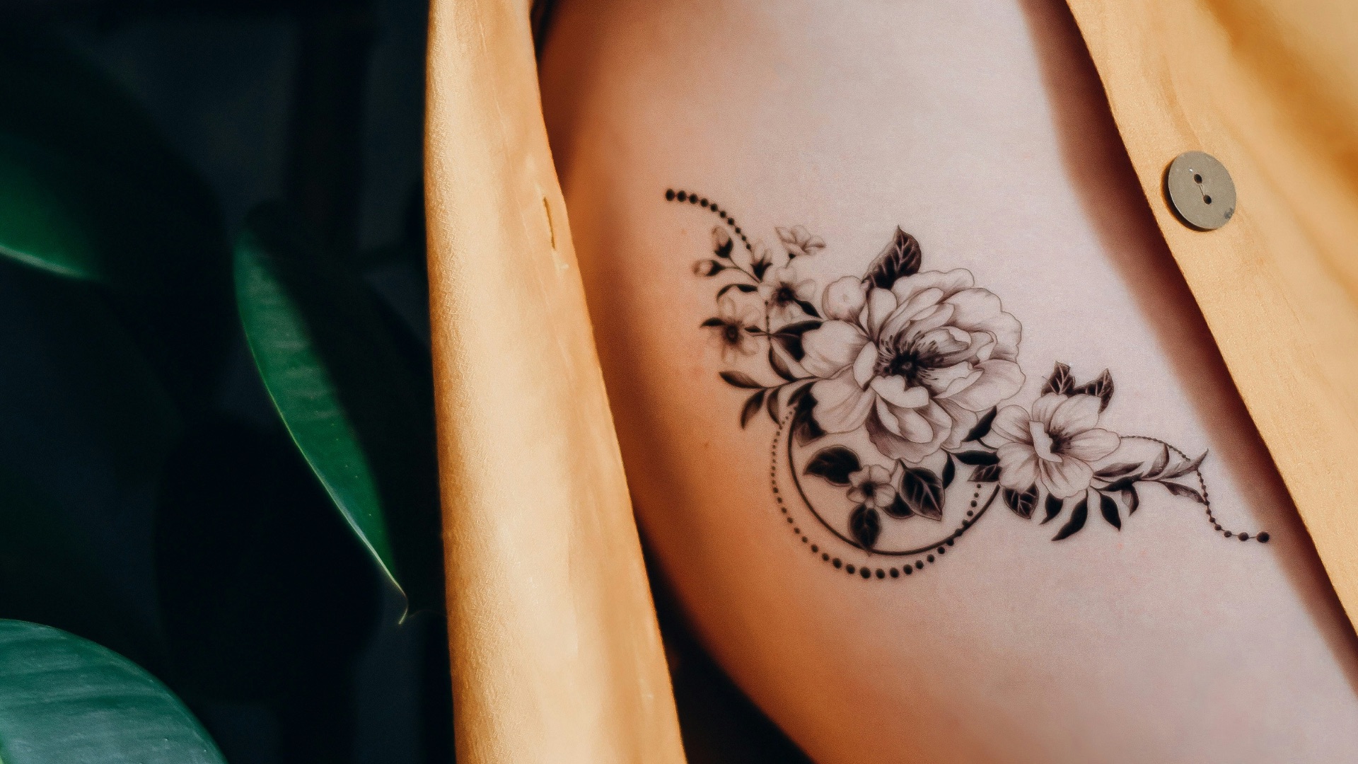 woman in orange button up shirt with black floral tattoo on her back