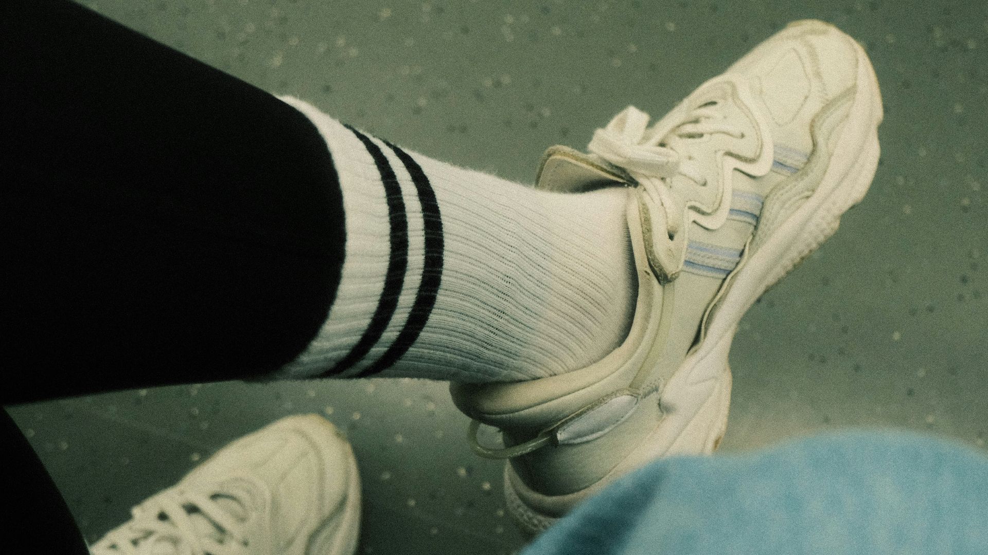 A person wearing white tennis shoes and black pants