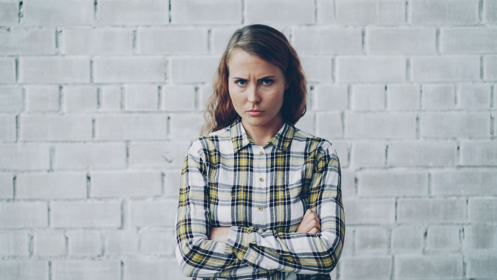 Young woman with arms crossed looks annoyed.