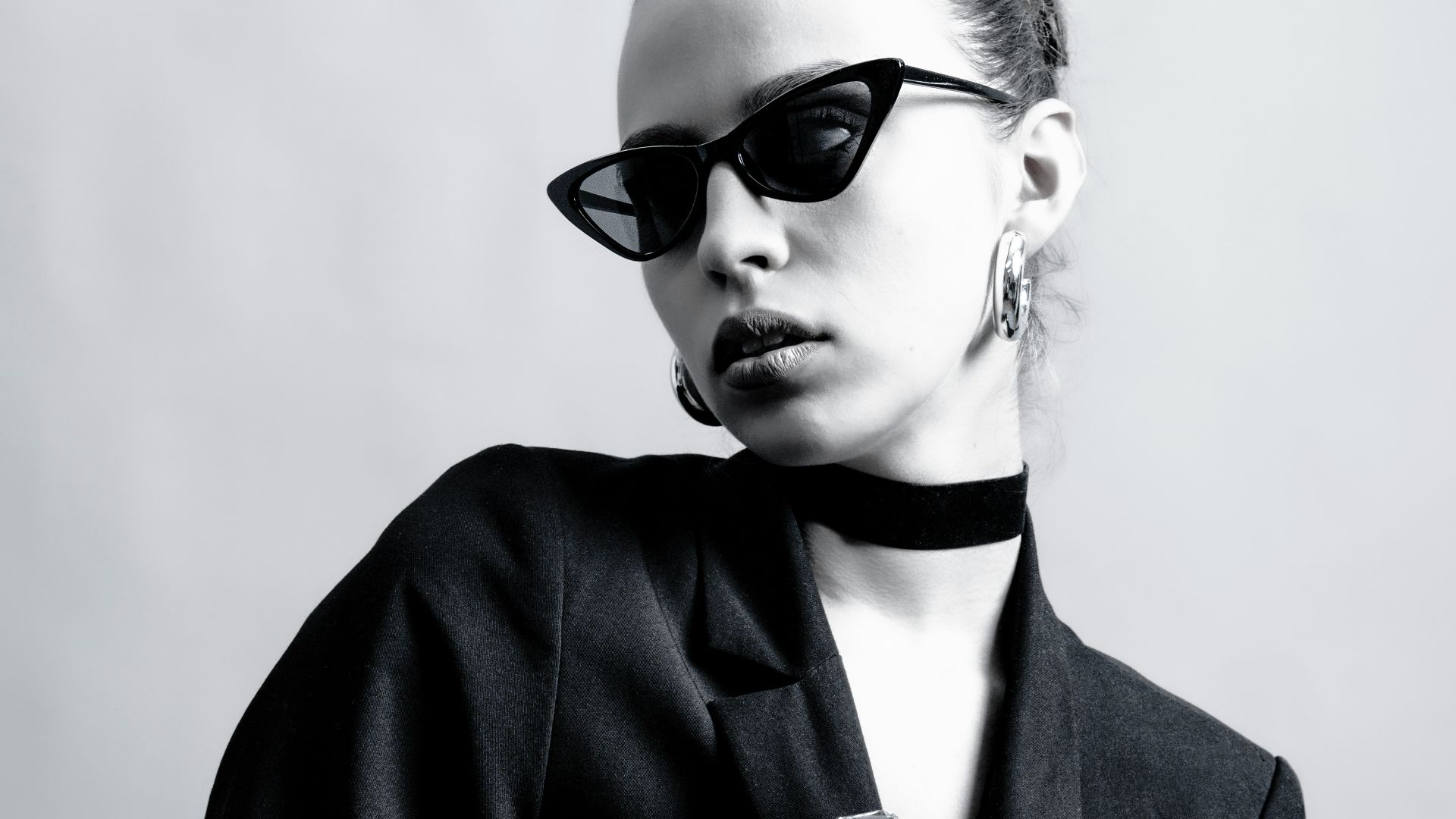 Stylish woman in black attire and sunglasses.