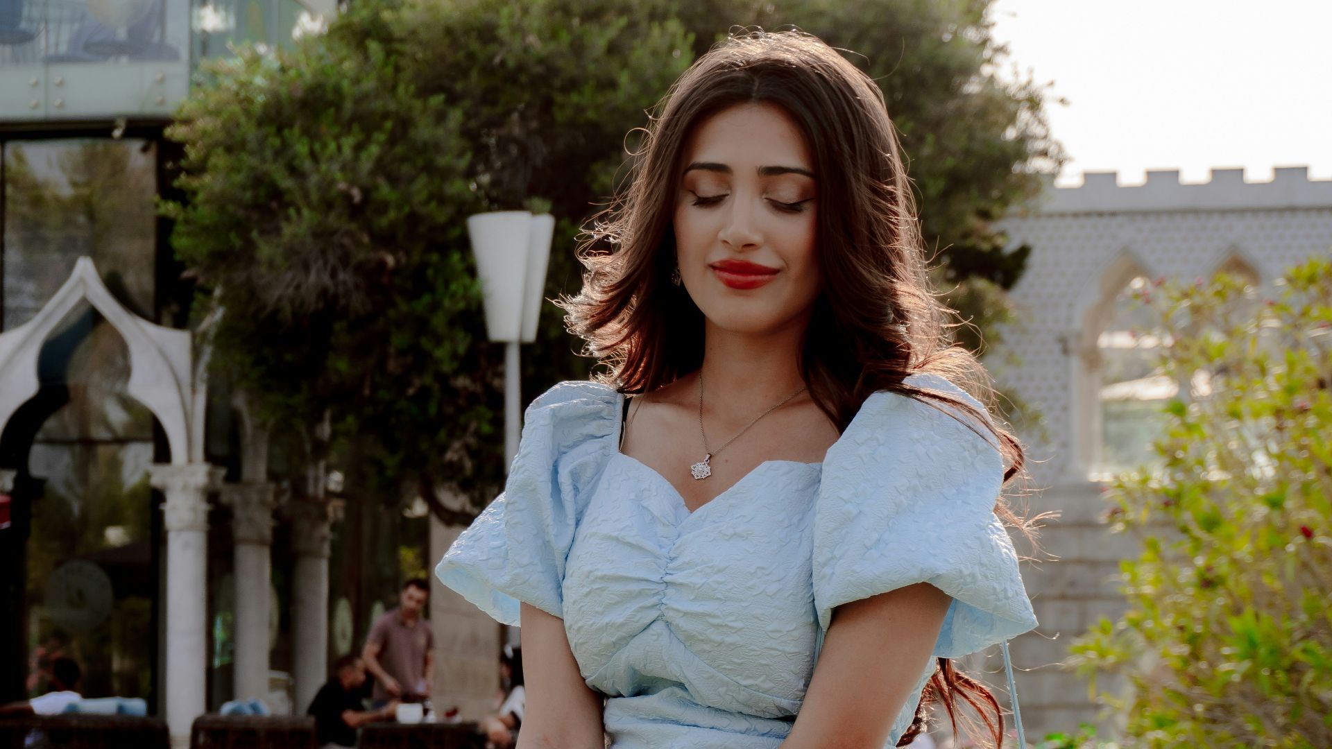 Young woman in light blue dress kneeling in grass