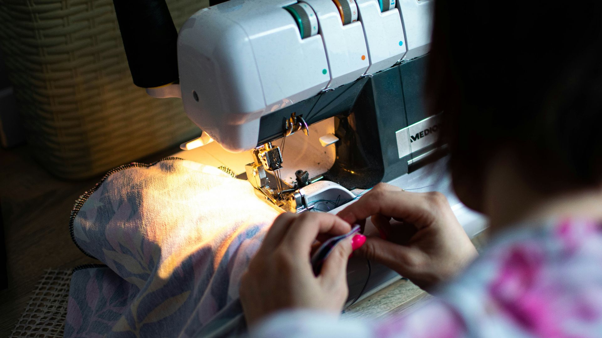 person sewing white sewing machine