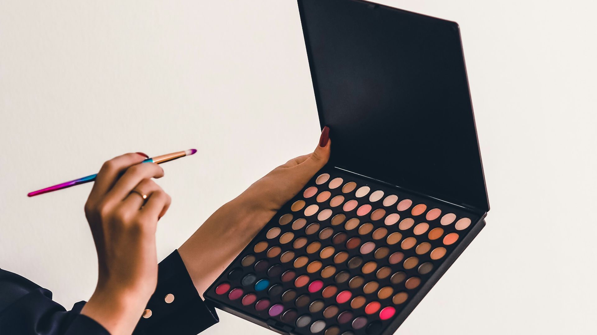 a person holding a makeup palette and a pencil